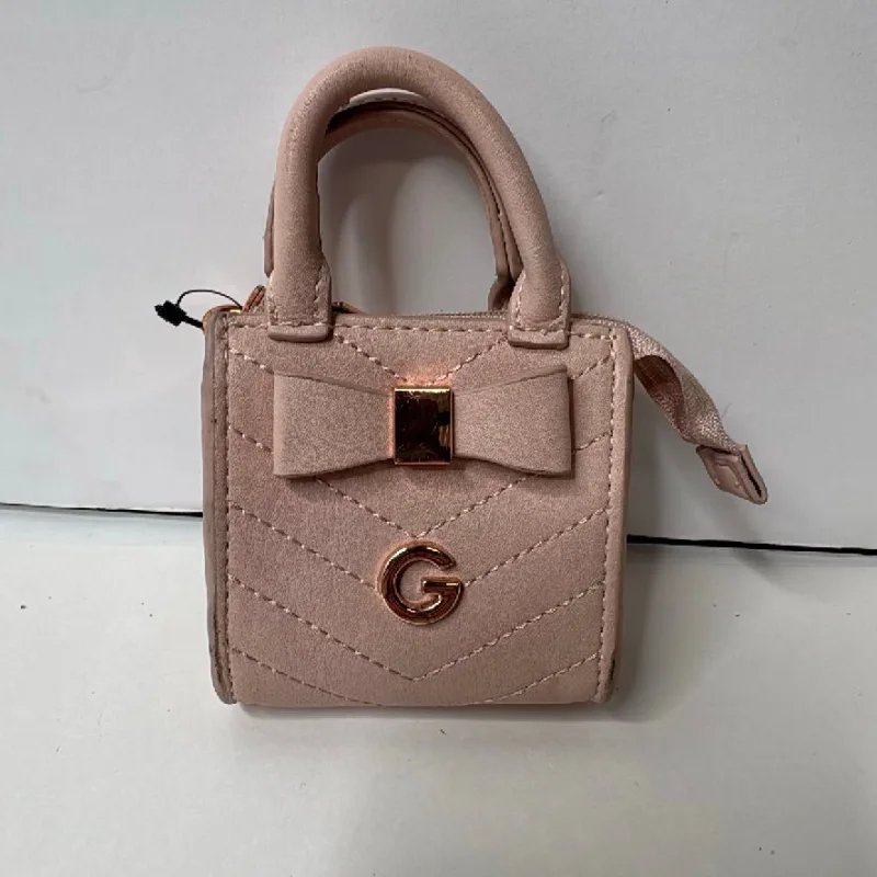 A pink quilted GUESS mini handbag photographed lying flat against a wall.